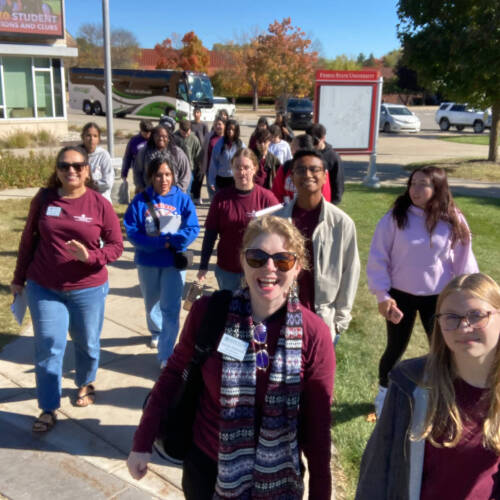 A group of students and staff walking toward the camera on a nice day.
